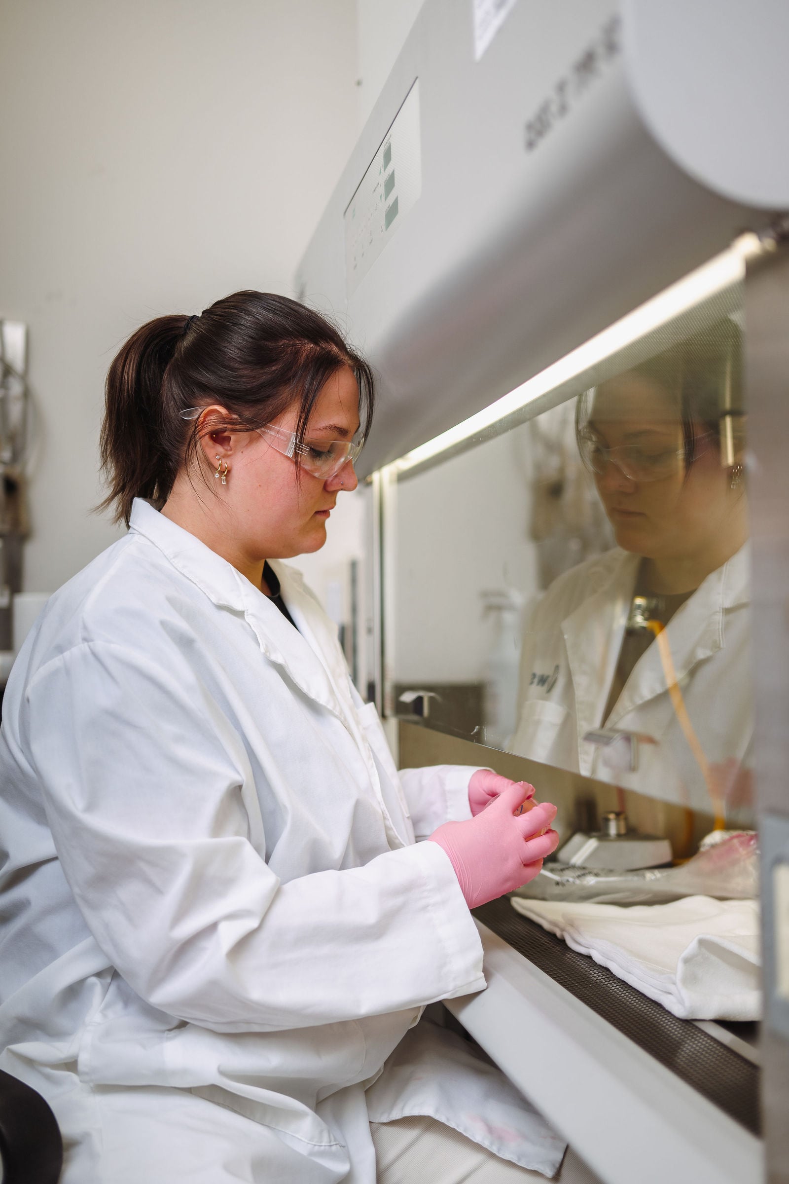 Lab technician working at fume hood with safety gloves